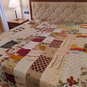 May include: A patchwork quilt featuring a mix of colours and patterns, including floral, geometric, and paisley designs. The quilt is made from cotton fabric and is hand-stitched. It's a beautiful and unique piece of art that would add a touch of bohemian style to any bedroom.