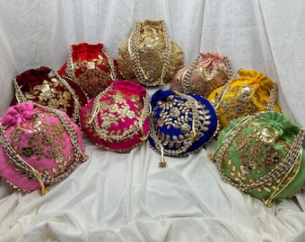 May include: Assortment of nine colorful drawstring bags with intricate embroidery and pearl embellishments. The bags are made of velvet and feature floral patterns in gold, silver, and other colors.