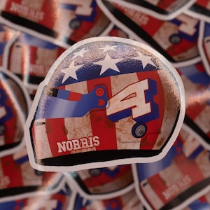May include: A red, white and blue sticker featuring a racing helmet design. The helmet has the number "4" on the side and the name "NORRIS" printed on the front.