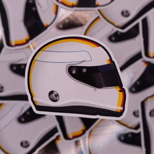 Puede incluir: Un casco de carreras blanco con una visera negra y detalles amarillos y rojos. El casco tiene una franja azul en la parte superior.
