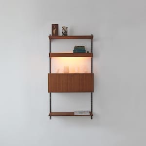 May include: A vintage wall-mounted shelving unit with a wooden cabinet and shelves. The unit features a warm wood finish, black metal supports, and internal lighting. Books and decorative objects are arranged on the shelves, creating a stylish display.