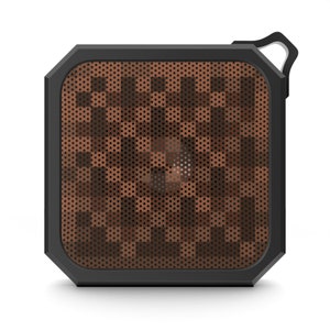 May include: A square portable speaker with a black frame and a brown, pixelated speaker grill. It features a small, white loop for attaching a lanyard. The design is modern and compact, suitable for travel.