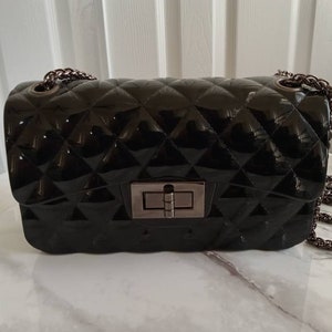 Bolso de mano acolchado negro con correa de cadena color metal. Nuevo.