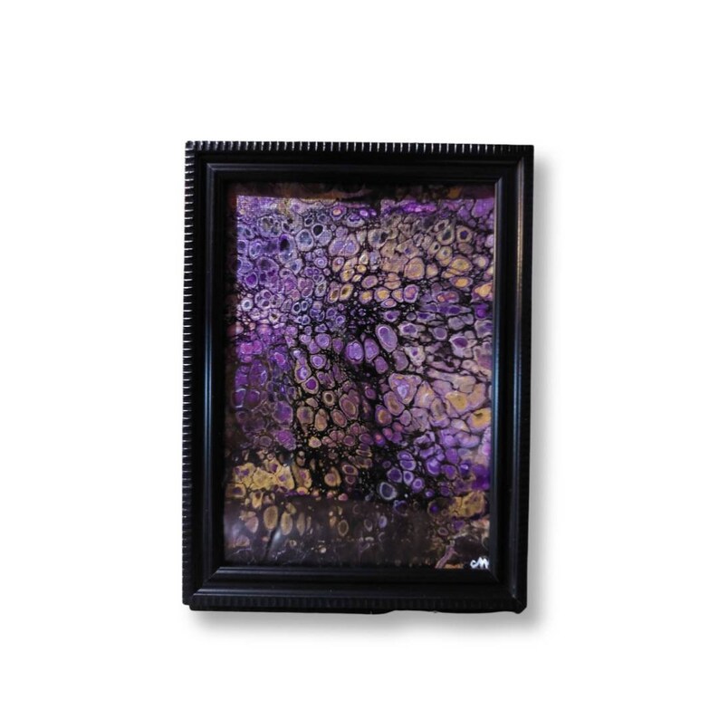 May include: Abstract painting in a black frame with purple, gold, and black colors. The painting has a swirling, organic pattern.