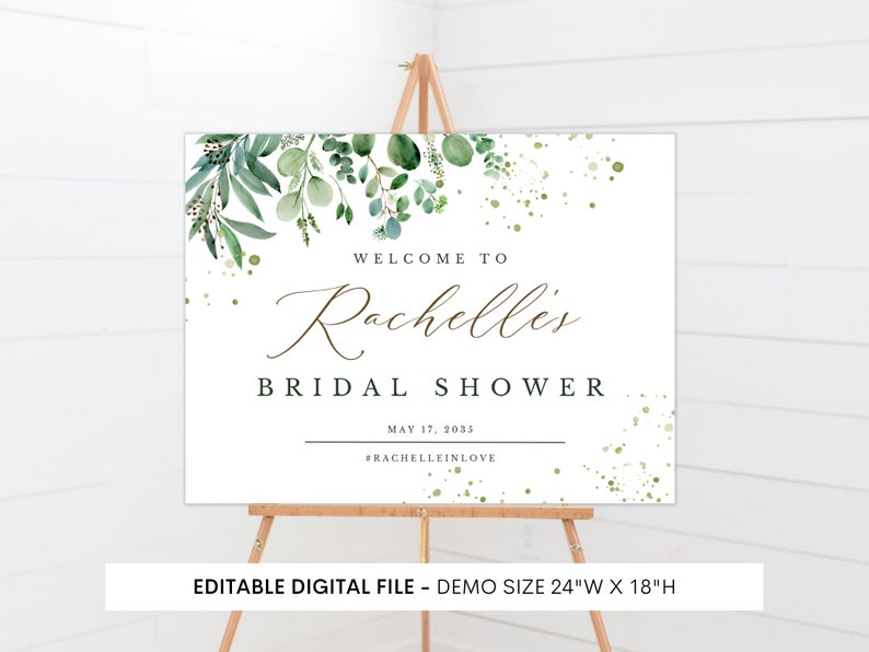 May include: A white welcome sign with green watercolor foliage and gold glitter accents. The text reads "Welcome to Rachelles Bridal Shower May 17, 2035 #Rachelleinlove". The sign is 24 inches wide by 18 inches high.