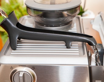May include: A stainless steel espresso machine with a black water reservoir and a water spout. The machine has a control knob with the word "STANDBY" printed on it.