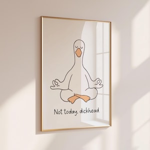 May include: A framed wall art print featuring a minimalist black line drawing of a white goose sitting in a lotus meditation pose with orange feet and beak. Below the goose, the text reads, "Not today, dickhead." in a simple black font.