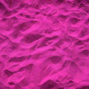 May include: A close-up of pink sand with a textured surface. The sand is soft and fine, creating a smooth and even surface.
