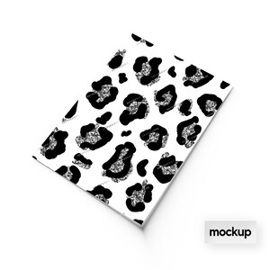 May include: A white sheet of paper with a black and silver glitter leopard print pattern. The paper is folded in half and the word "mockup" is printed in black on a white rectangle at the bottom of the image.