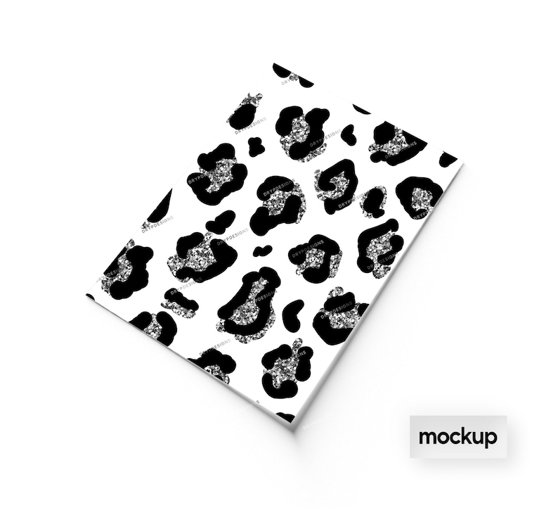 May include: A white sheet of paper with a black and silver glitter leopard print pattern. The paper is folded in half and the word "mockup" is printed in black on a white rectangle at the bottom of the image.