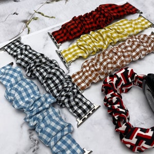 May include: Five different patterned watch bands for Apple Watches. The bands are made of a soft, stretchy fabric with a gingham pattern. The bands are in red and black, yellow and white, brown and white, black and white, and blue and white.