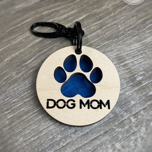 May include: A wooden keychain with a blue paw print cutout and the text "DOG MOM" engraved on it.