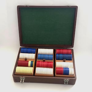 May include: A brown rectangular carrying case with a green felt-lined interior lid, containing three wooden compartments filled with stacks of round plastic poker chips in red, white, blue, and yellow colors, secured by two metal front latches.