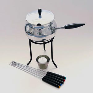 May include: A silver-toned metal fondue pot with a lid and a black handle, resting on a black metal stand. A small metal cup holds a white tea light candle. Five metal fondue forks with black handles and colored tips are arranged in front.