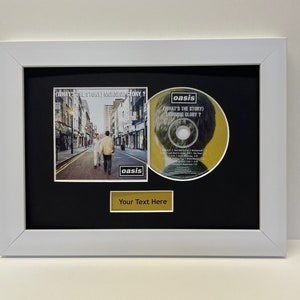 May include: A white framed display with a black mount featuring a CD and a CD cover. The CD cover is for the Oasis album "What's the Story (Morning Glory)?". The CD is also for the Oasis album "What's the Story (Morning Glory)?". The mount has a gold plaque with the text "Your Text Here".