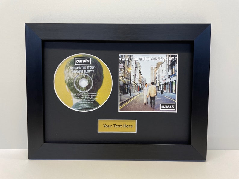 May include: A framed CD and album cover of Oasis's "What's the Story (Morning Glory)?" album. The CD is in a black frame with a gold plaque that says "Your Text Here".