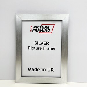May include: Silver picture frame with a white mat and the text "KWIK PICTURE FRAMING" in red. The frame is made in the UK.