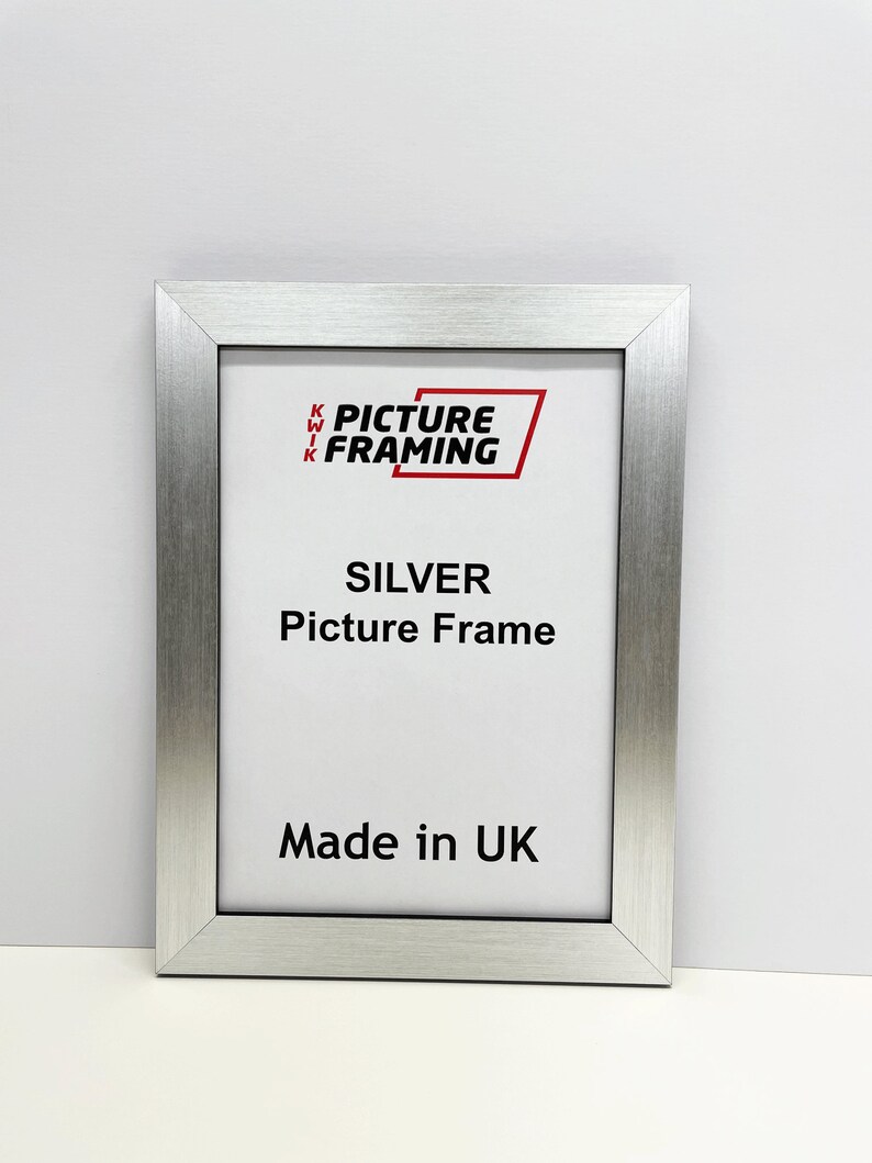 May include: Silver picture frame with a white mat and the text "KWIK PICTURE FRAMING" in red. The frame is made in the UK.
