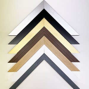 May include: A set of six picture frames with different colored frames. The frames are arranged in a pyramid shape, with the largest frame at the top and the smallest frame at the bottom. The frames are made of wood and metal, and they are all in different colors, including silver, black, gold, brown, white, and gray.