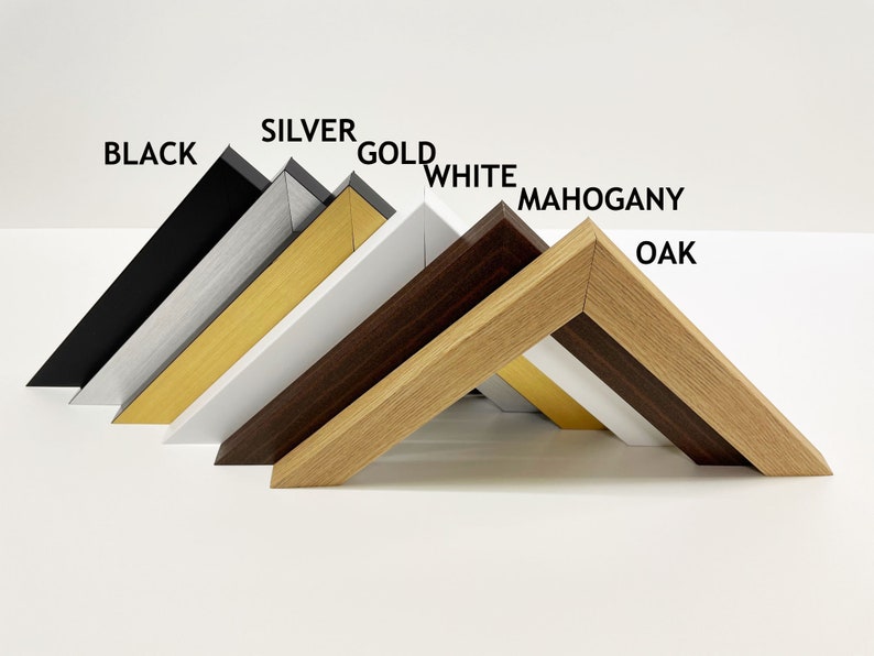 May include: Close-up of six picture frames in different colors, including black, silver, gold, white, mahogany, and oak. The frames are arranged in a row, with the black frame at the top and the oak frame at the bottom.