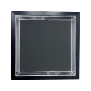 May include: A square display case with a black frame and a clear acrylic front. The interior is a dark grey, creating a shadow effect. The frame is made of a dark wood or composite material. The case is designed to showcase items.