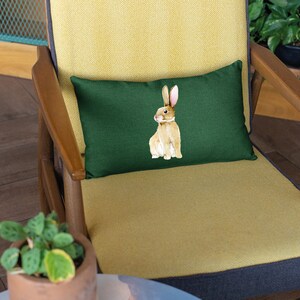 May include: A green cushion with a brown rabbit illustration on a yellow armchair.