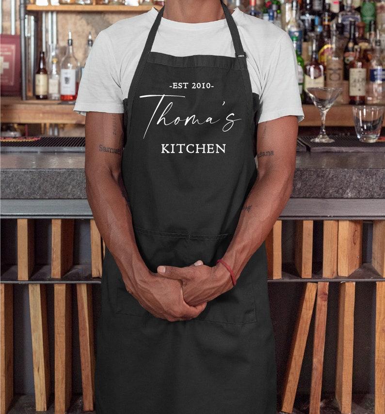 May include: Black apron with white text that reads "EST 2010 - Thomas's Kitchen".