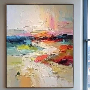 May include: Large abstract painting with a textured surface. The artwork features a landscape with a palette of colors including white, pink, orange, blue, green, and red. The painting is framed and displayed on a white wall.