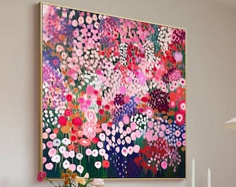 May include: A large abstract painting featuring a field of pink, red, and purple flowers on a dark green background. The painting is framed in gold and hangs on a white wall above a wooden dresser.