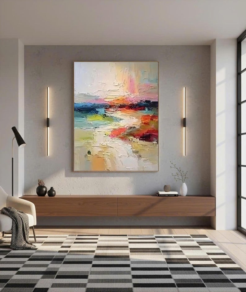 May include: An abstract oil painting with a textured surface, featuring a landscape of blended colors. The artwork showcases hues of blue, green, orange, and red, creating a vibrant and dynamic composition. The painting is displayed above a wooden cabinet.
