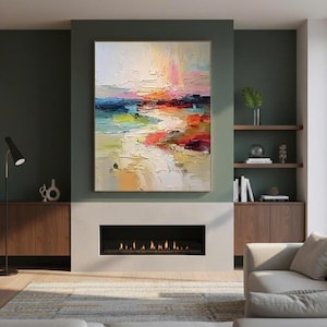 May include: An abstract landscape painting with a gold frame. The artwork features a textured, colorful composition with strokes of white, yellow, blue, red, and pink. The painting hangs above a fireplace in a modern living room.