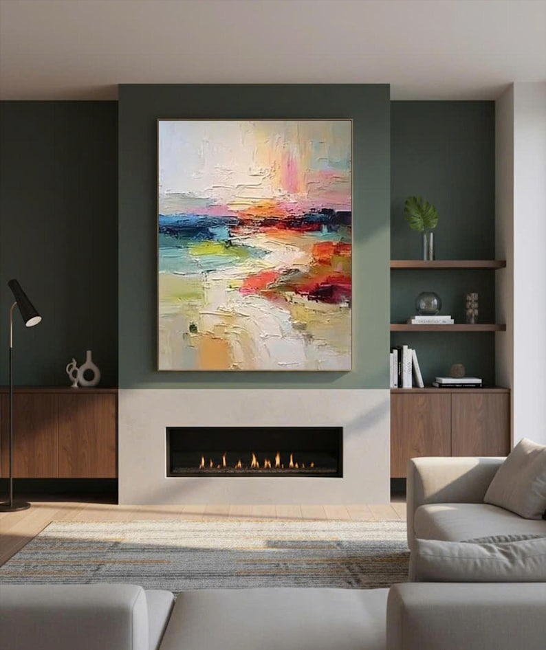 May include: An abstract landscape painting with a gold frame. The artwork features a textured, colorful composition with strokes of white, yellow, blue, red, and pink. The painting hangs above a fireplace in a modern living room.