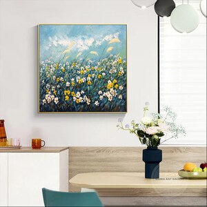 K&ouml;nnte beinhalten: Ein Gem&auml;lde, das ein Feld mit wei&szlig;en und gelben Blumen zeigt, in dem hohes Gras im Wind weht, vor einem blauen Himmel mit wei&szlig;en Wolken.