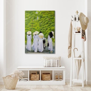 May include: A painting of four people wearing white ao dai dresses and conical hats walking down a path in a green forest. The people are walking in a line, and the person in the back is riding a bicycle.
