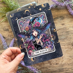 May include: A decorative card with a witch illustration. The witch has blue and purple hair, a black hat with flowers, and a black cat. The card is framed with moons and stars, and the text "THE WITCH" is visible.