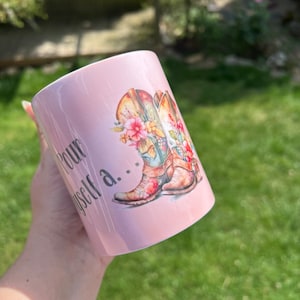 May include: Pink ceramic mug with a floral design featuring cowboy boots and the text "Pour yourself a..."
