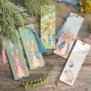 May include: Five colourful bookmarks featuring illustrations of Peter Rabbit characters. The bookmarks are rectangular and have a tassel at the top. The characters include Peter Rabbit, Benjamin Bunny, and a duck.