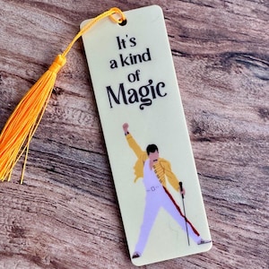 May include: A yellow bookmark with a tassel features a silhouette of a person with a microphone and the text "It's a kind of Magic".