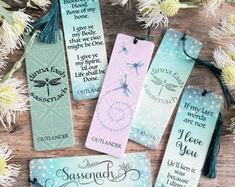 May include: Set of six Outlander themed bookmarks featuring a dragonfly design and quotes from the book series. The bookmarks are printed on cardstock with a green, blue, or pink background and have a tassel.