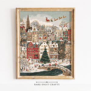 May include: A framed art print depicting a snowy winter cityscape with multi-storey buildings, a large central Christmas tree, and a bridge over a dark river. Santa Claus and his reindeer fly across the sky above the town, while small figures walk.