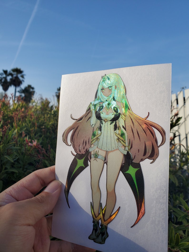 May include: A sticker featuring a female anime character with long green hair, wearing a white and green outfit with gold accents. The character has a green and black star-shaped design on her legs and wings.