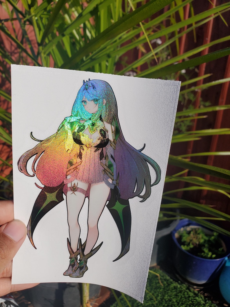 May include: A holographic sticker featuring a female anime character with long blue hair, wearing a white and green outfit with a rainbow iridescent finish. The character is holding a green gem in her hands.