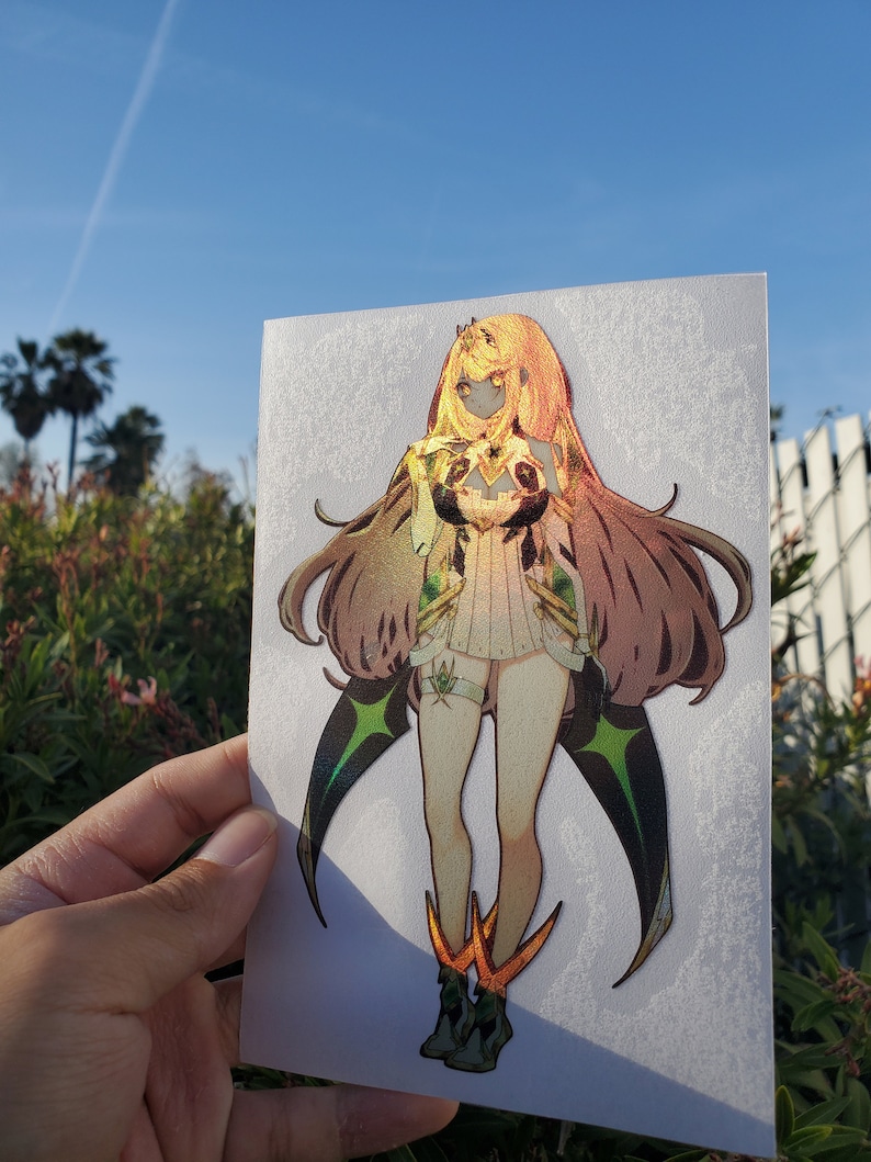May include: A holographic sticker featuring a female anime character with long brown hair, wearing a white and green outfit with gold accents. The character is standing with her arms crossed and has a serious expression.