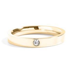 Könnte beinhalten: Ein goldfarbener Edelstahlring mit einem einzigen klaren Strassstein in der Mitte.