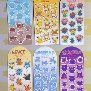 Peut inclure: Six planches d'autocollants avec des personnages de dessins animés. Les planches sont étiquetées "WOOPER", "CHUCHU", "ODDISH", "EEVEE", "MARILL" et "GRAAH!". Chaque planche a une palette de couleurs unique et présente plusieurs autocollants du même personnage.