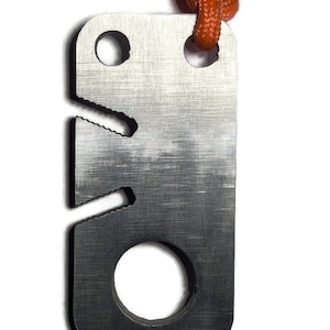 May include: A silver metal keychain with a serrated edge, a hole for a lanyard, and a round hole for a key. The keychain is attached to an orange lanyard.