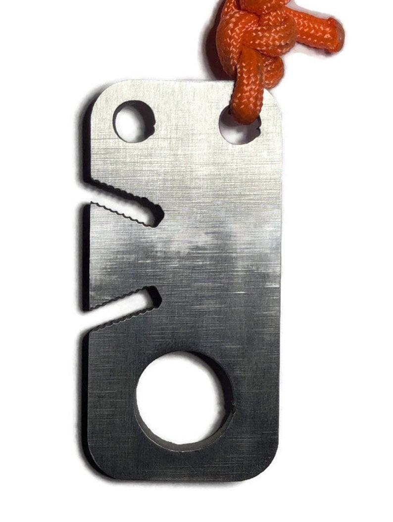 May include: A silver metal keychain with a serrated edge, a hole for a lanyard, and a round hole for a key. The keychain is attached to an orange lanyard.