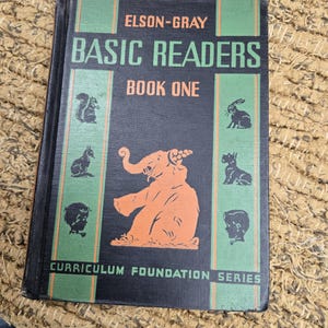 May include: A vintage "Basic Readers Book One" textbook. The cover is dark blue with green and orange accents. It features illustrations of animals and the text "ELSON-GRAY" and "CURRICULUM FOUNDATION SERIES".