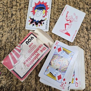May include: A vintage deck of playing cards with a red and white box. The deck includes two joker cards and several cards from the diamond suit. The box reads "YOU and the winning combination".
