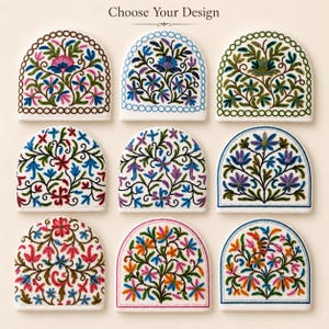 May include: Nine semi-circular fabric pieces arranged in a grid, each featuring unique floral embroidery in various colors. The text "Choose Your Design" is centered at the top. The designs include intricate stems, leaves, and blossoms.